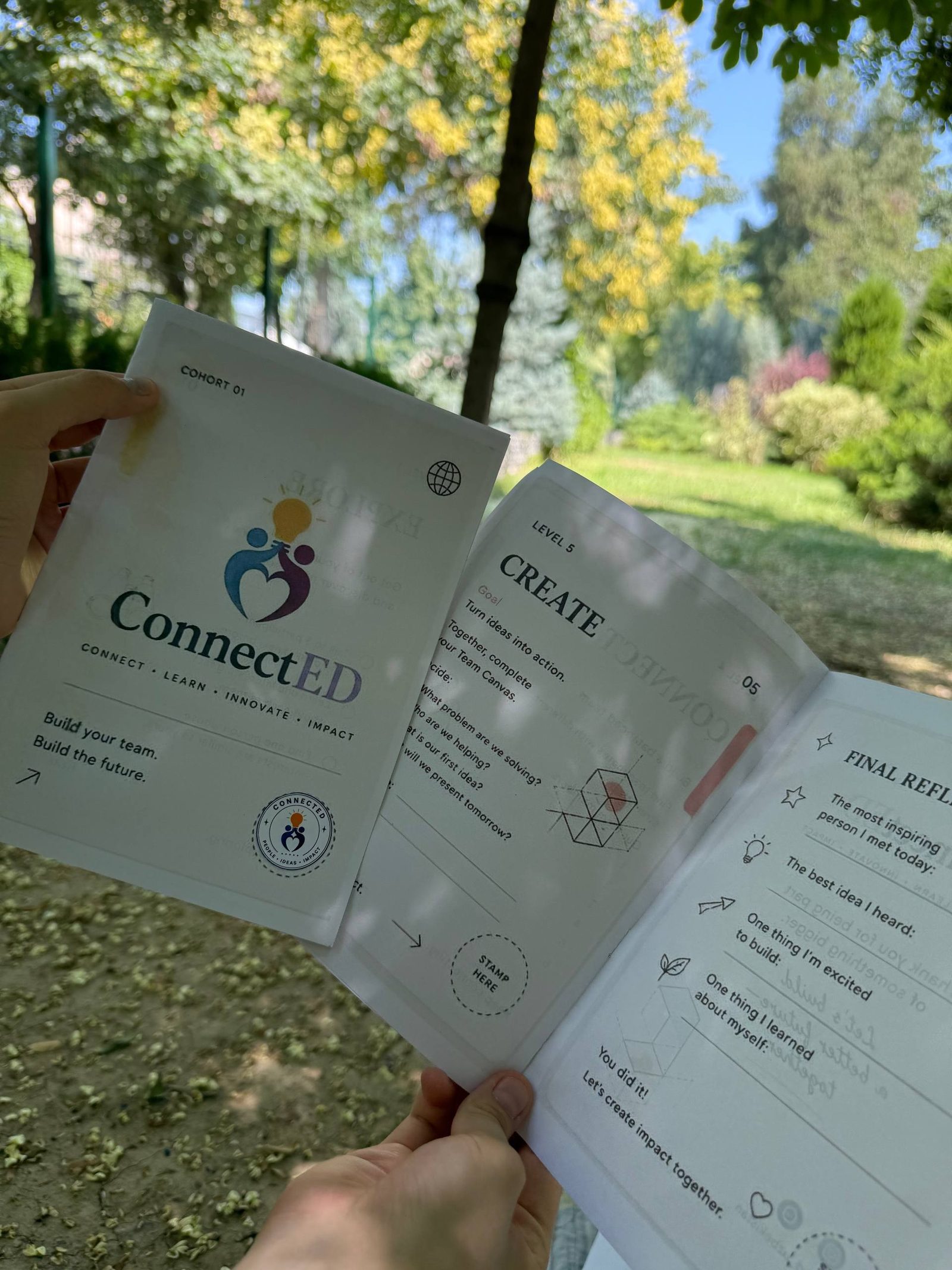 A ConnectED participant holding up the program's passport booklet in a park