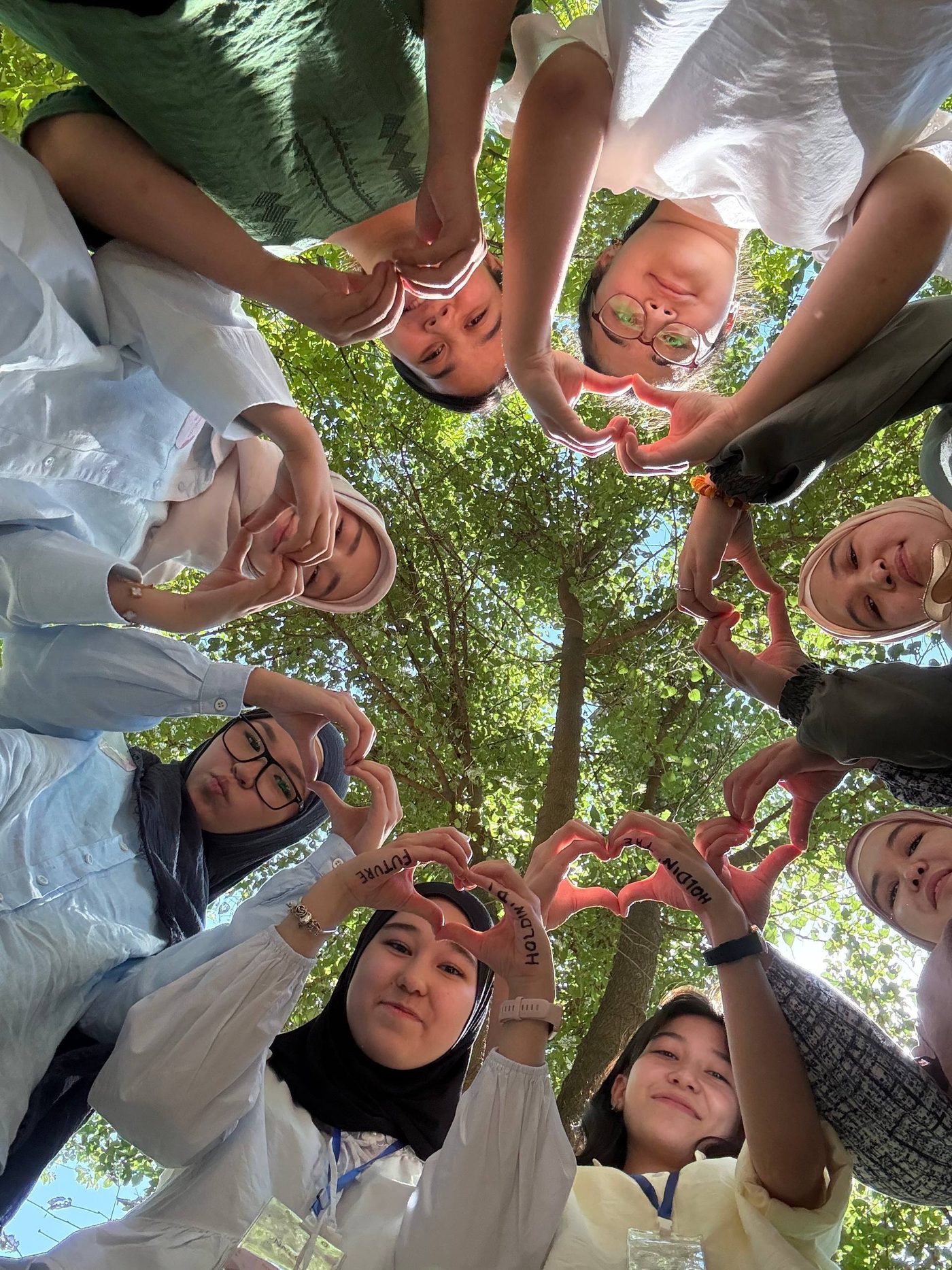 Cohort participants making heart shapes with their hands, photographed from below