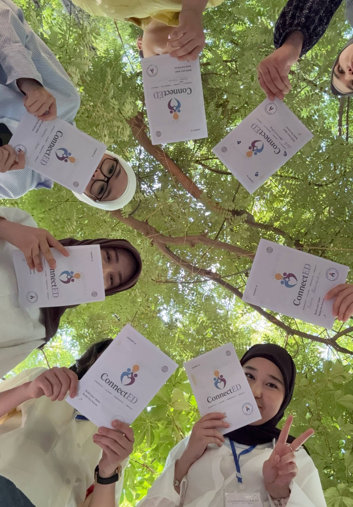 Cohort 1 participants holding their ConnectED passports under a tree