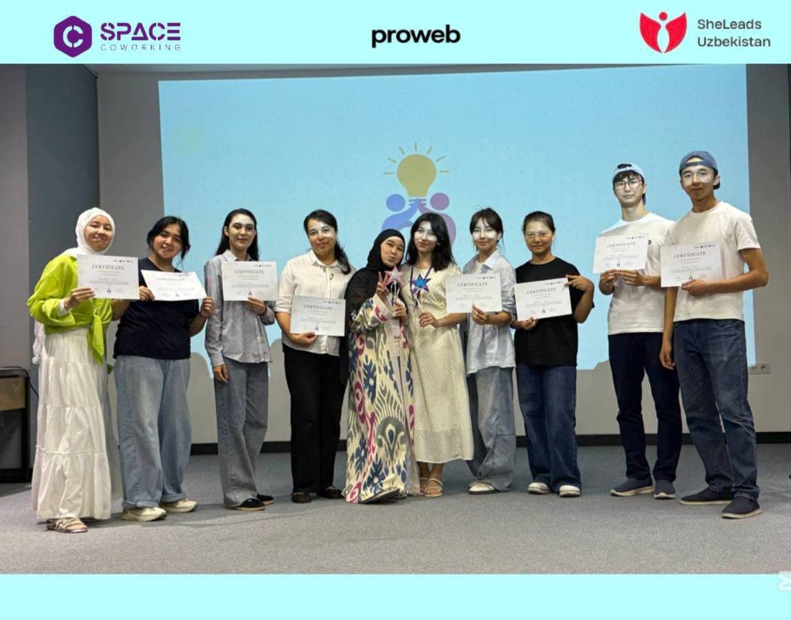 A cohort posing on stage with their certificates, with Space Coworking, proweb and SheLeads Uzbekistan logos on screen behind them